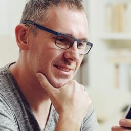 Hearing impaired man with hearing aid using smart phone at home or at office