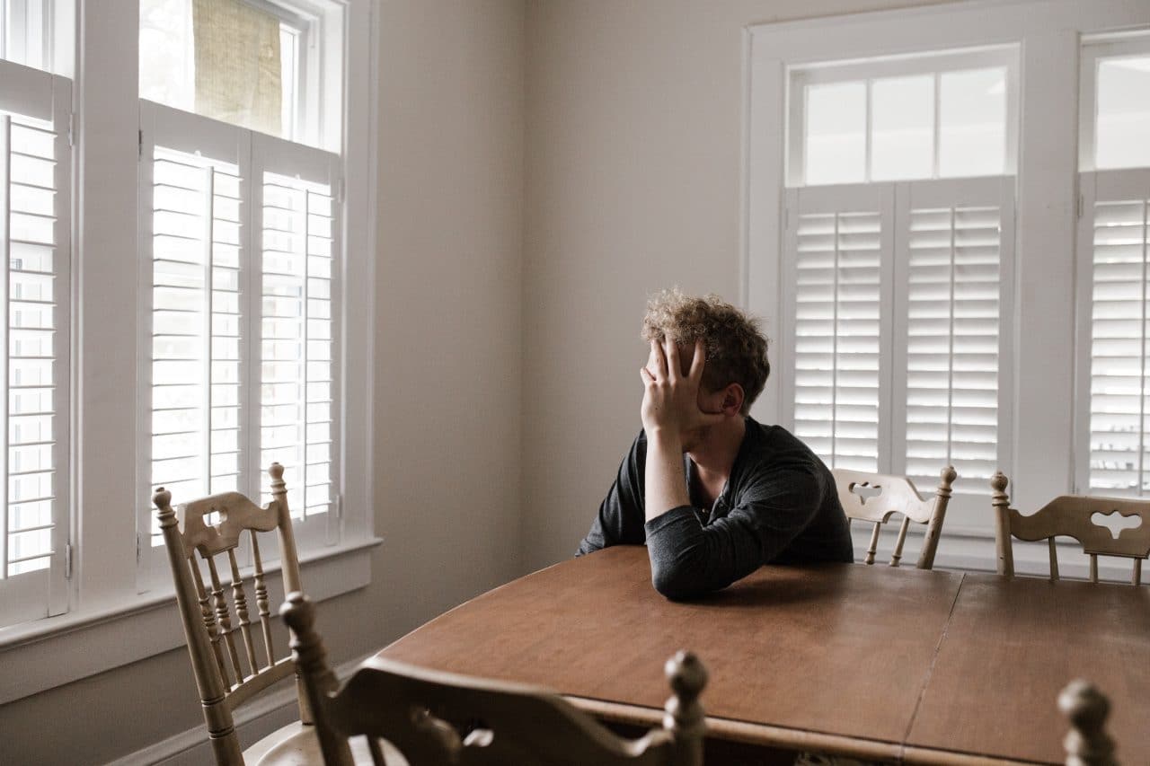 Frustrated man sitting at kitchen table.