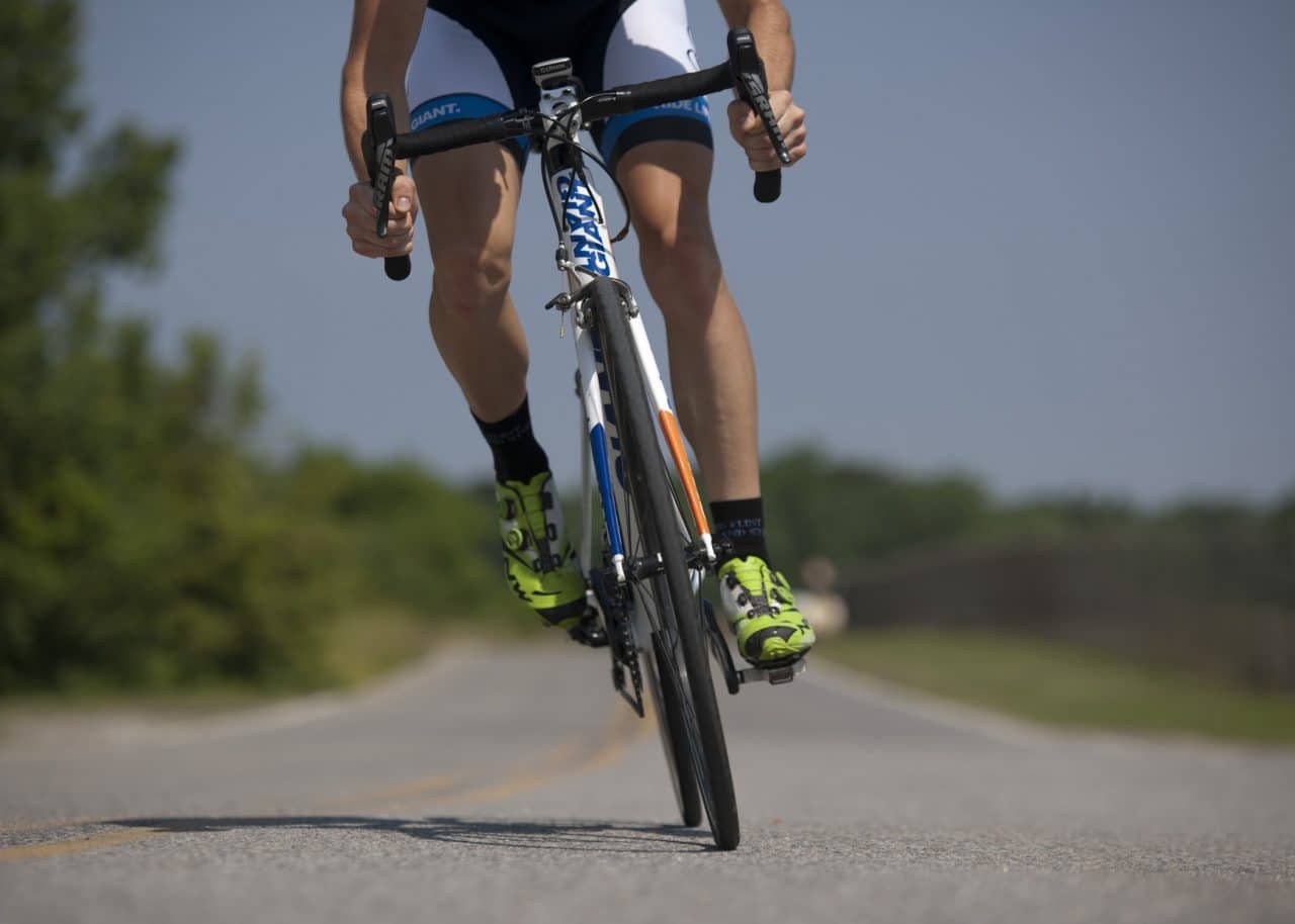 Close-up of man cycling on an open road.