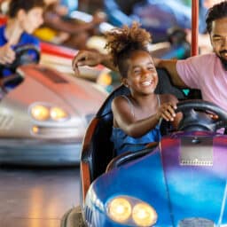 Father and daughter riding in a bumper car together.