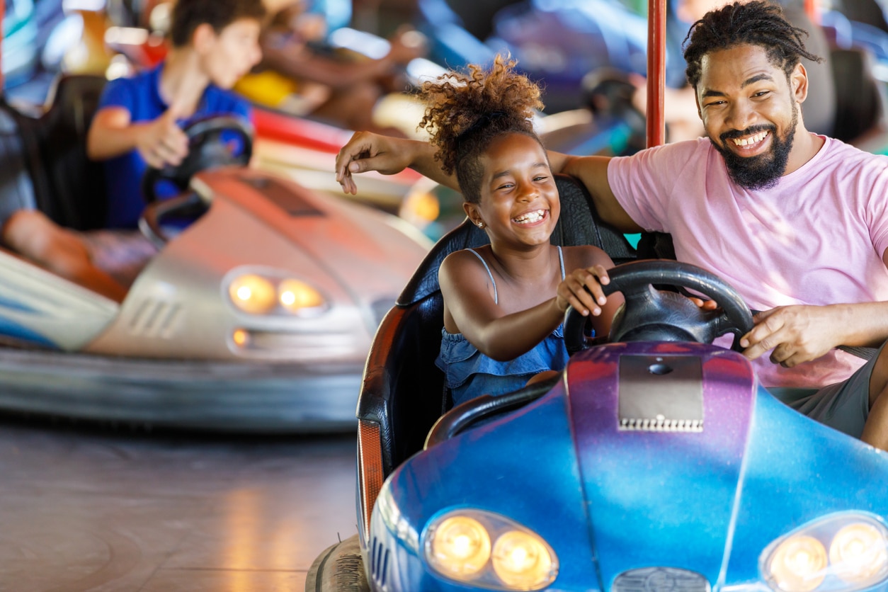 Father and daughter riding in a bumper car together. 