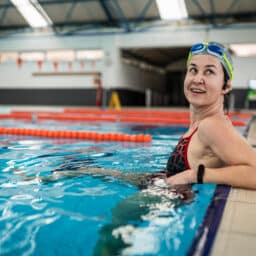 Happy woman sitting at the edge of a swimming lane.