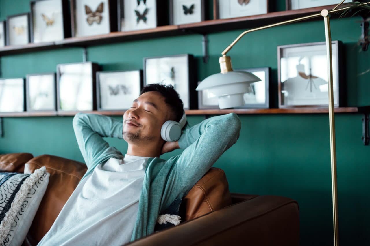 Man wears headphones for sound therapy for tinnitus. He is relaxed, finding relief from tinnitus.