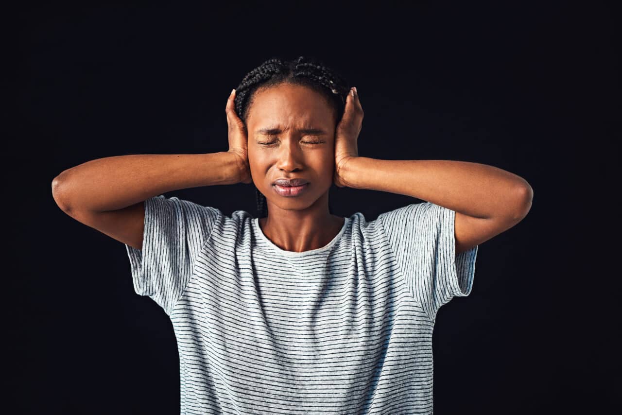 Woman struggling with loud noise, covers her ears.
