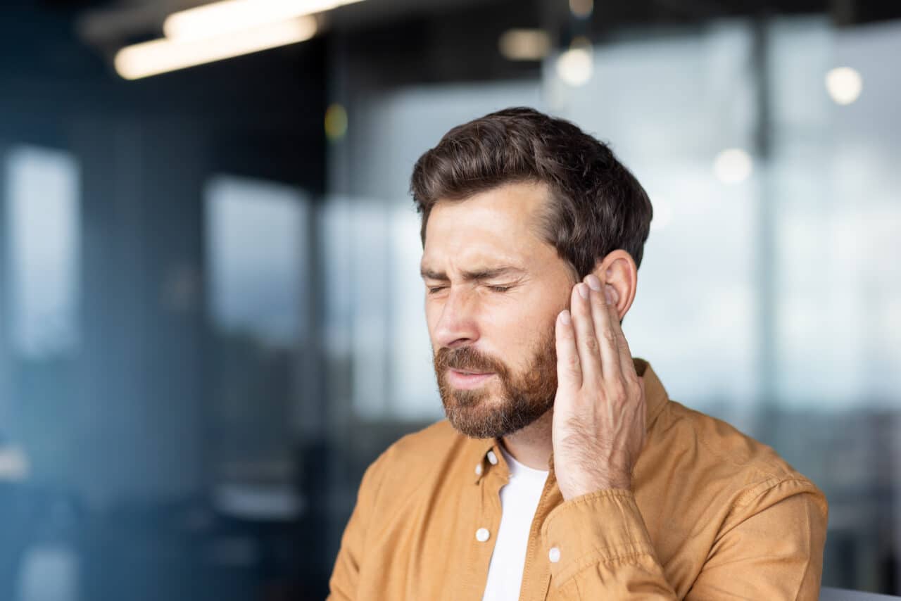 Man with tinnitus holds his ear.