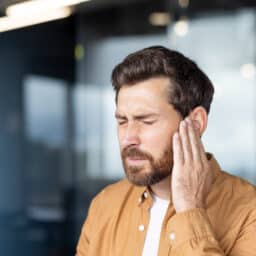 Man with tinnitus holds his ear.